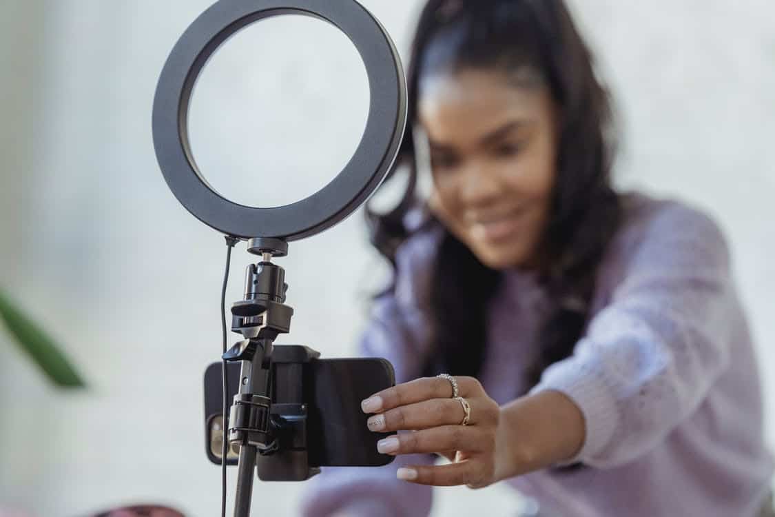 An influencer adjusting phone and ring light for recording a video