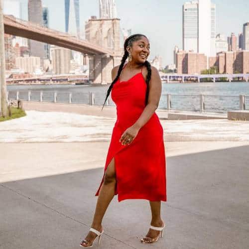 Adanna Dill walking along the Hudson River in a red dress
