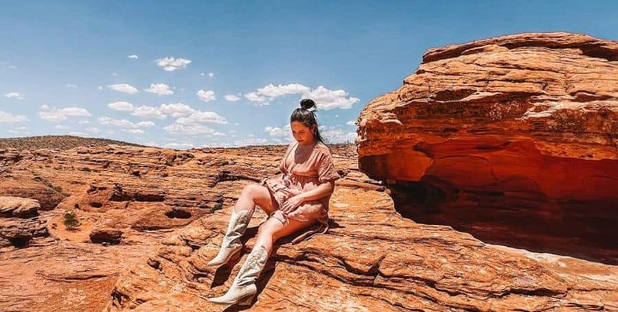 Aly Wednesday resting on red rocks after hiking in Utah
