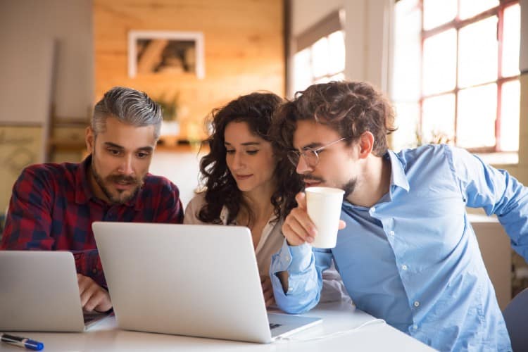 Brand marketing reps searching for nano-influencers on their laptops