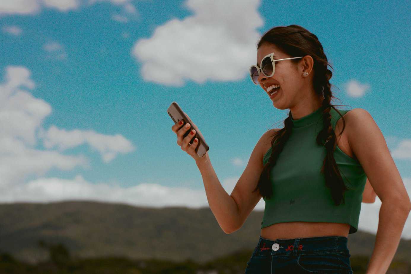 Micro-influencer in green crop top laughing while looking at her phone | Real estate marketing tips