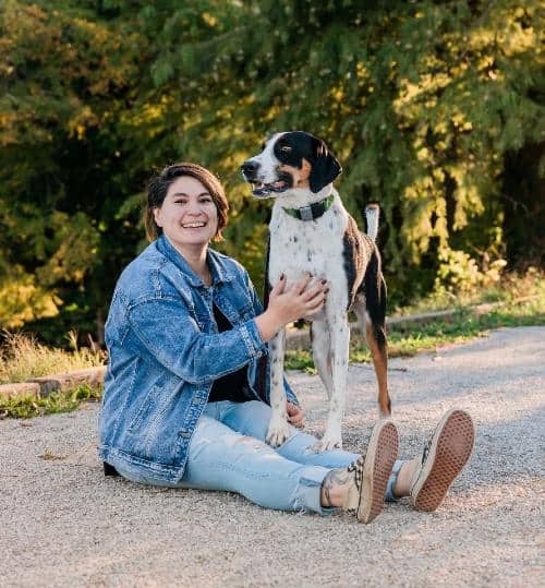 Caroline and her pet dog sitting on a gravel road