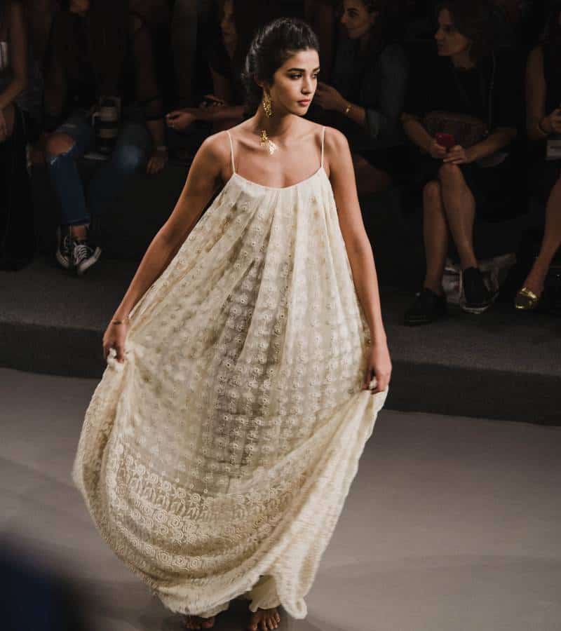Model on the catwalk wearing a breezy white dress with shoestring straps