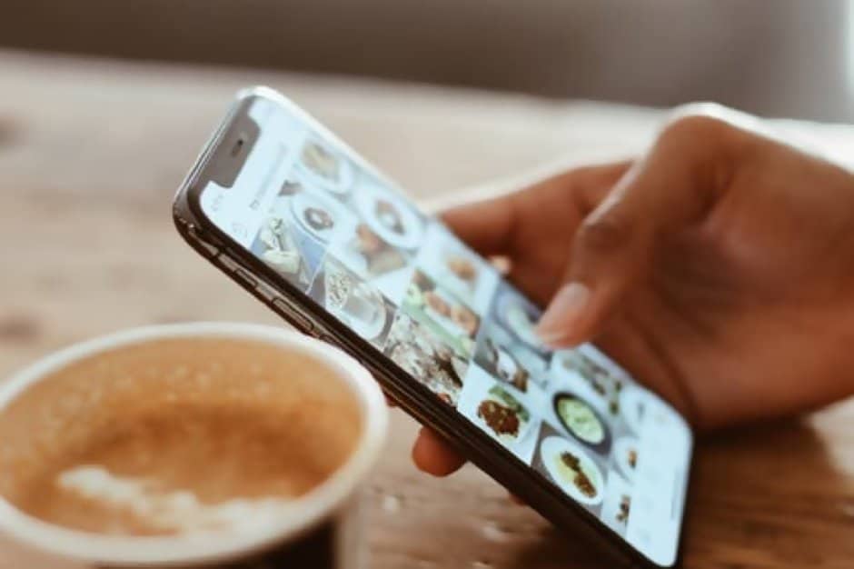 User scrolling through food image on social media with coffee on the side