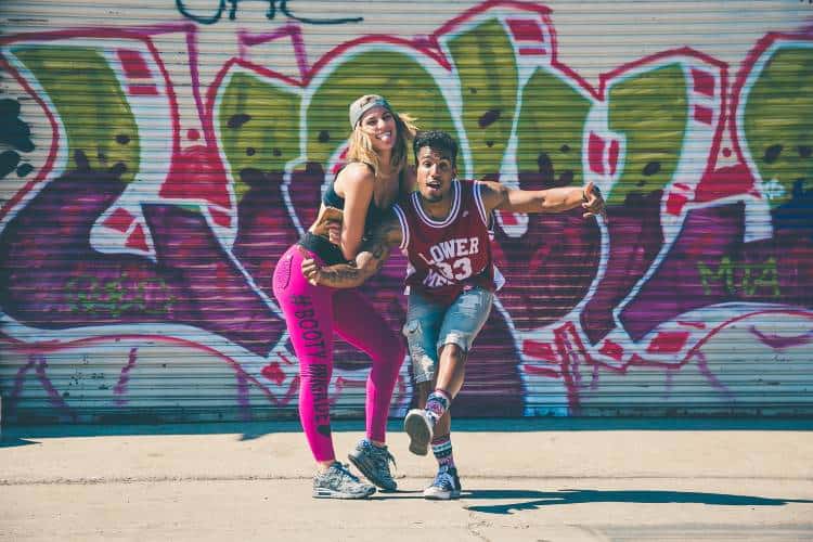 Man and woman street dancing with graffiti behind them