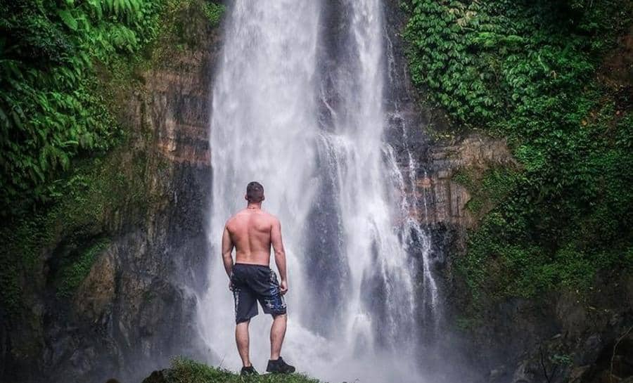 David the world travel guy standing at base of waterfall in Bali