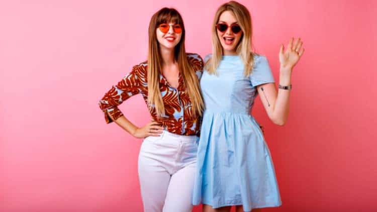 Two happy influencers posing with a pink background | Shopify Merchants