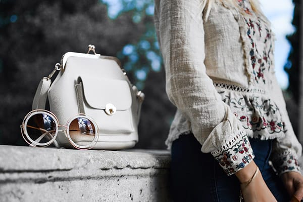 Influencer leaning on wall with hangbag and sunglasses