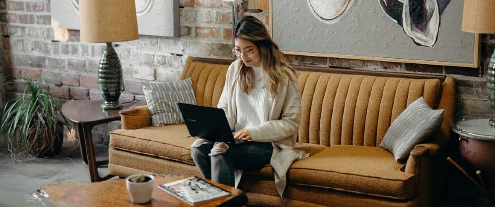 influencer working on Shopify marketing campaign while sat on sofa