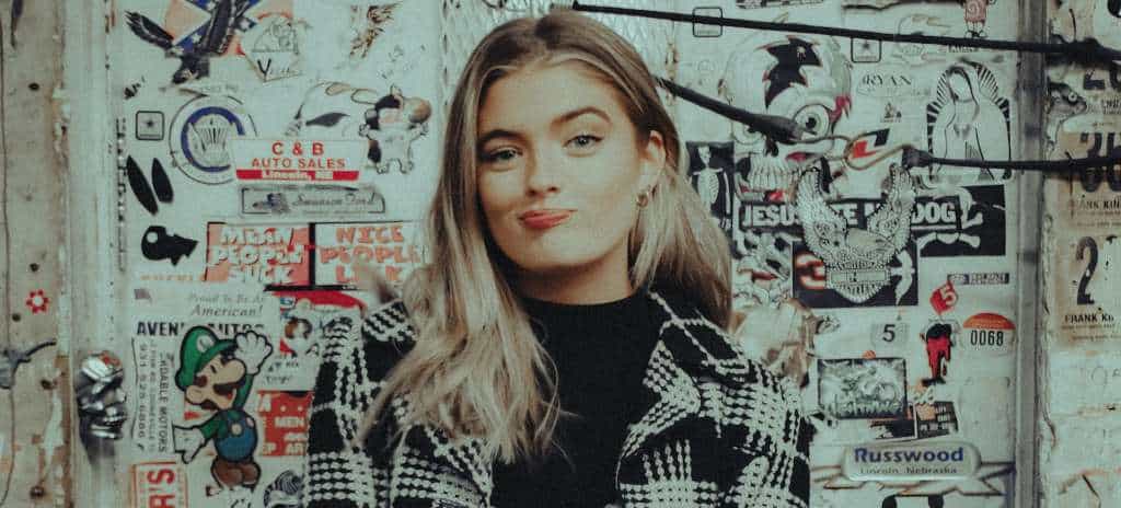 Influencer girl posing against a wall covered in stickers