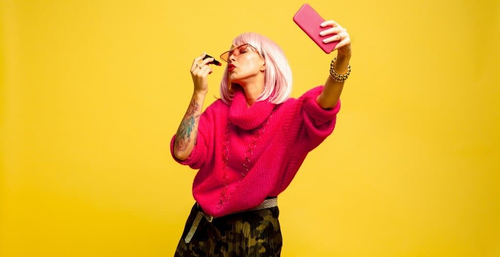 Beauty influencer applying lipstick while taking a selfie