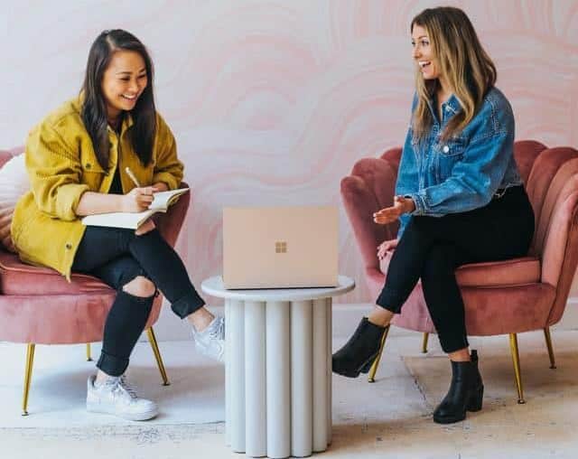Influencer women sat on chairs across from each otherchatting 