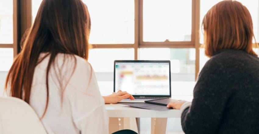 Two influencer women reviewing social insights on a laptop