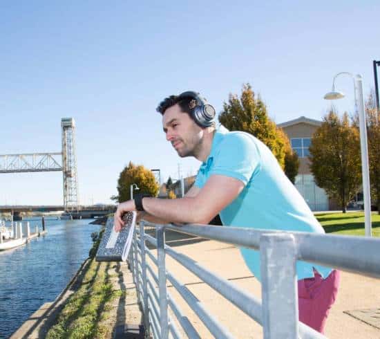 Jacob Morgan | Wearing headphones leaning on rail overlooking the river