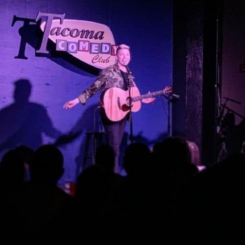 Kristin Key | On stage with guitar at Tacoma Comedy Club