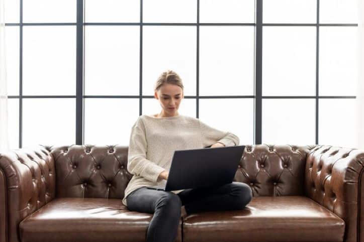 Woman sitting on leather sofa working from home on laptop | Influencer Marketing Changes in 2020