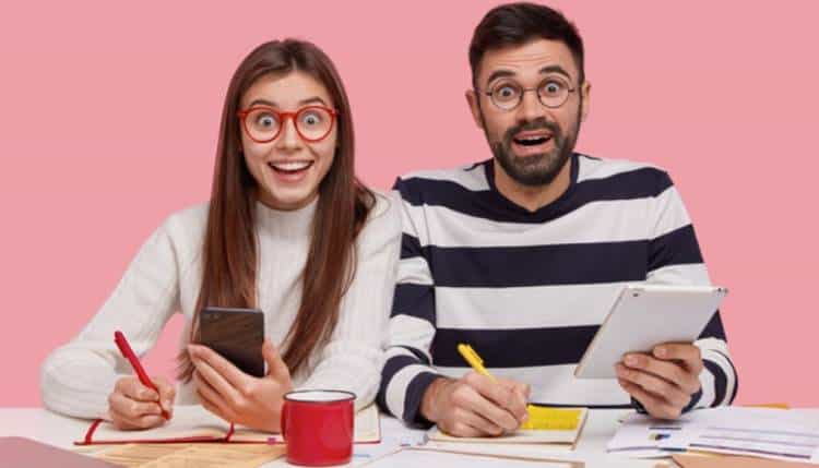 Couple taking notes while viewing their mobile devices