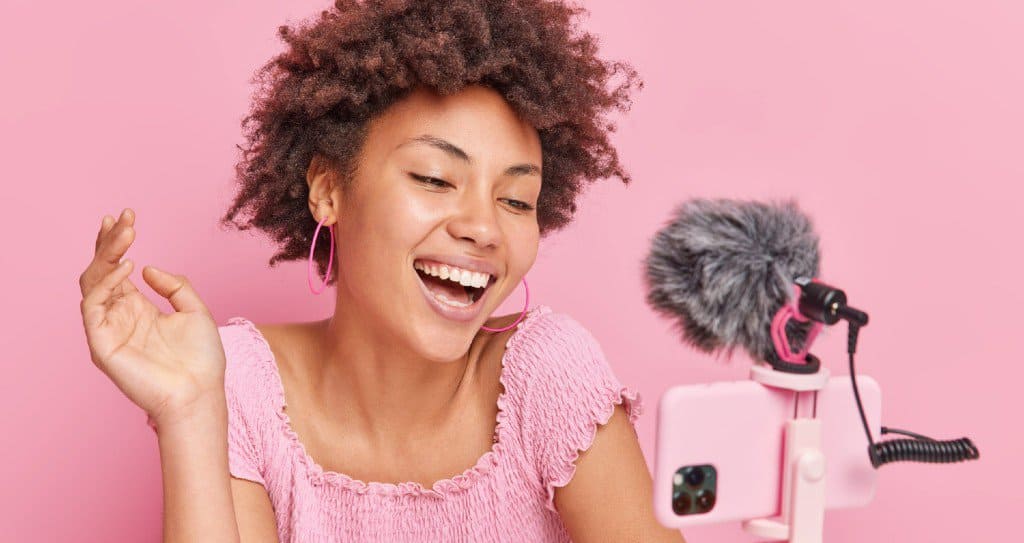 Micro-influencer in pink laughing to audience while making a video