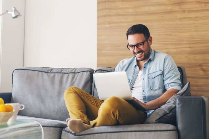 Man sitting on sofa being entertained by YouTube videos.