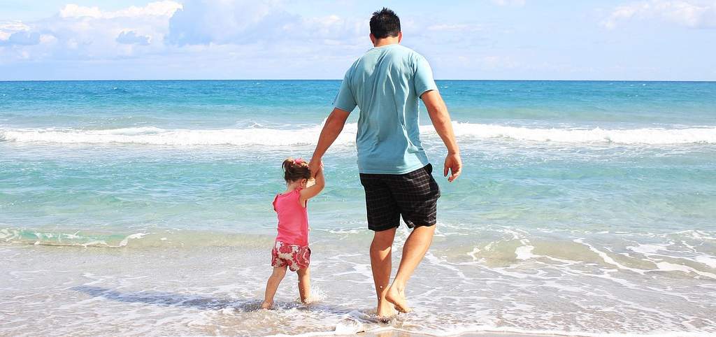 Traveling Families | Father and daughter walking on the beach