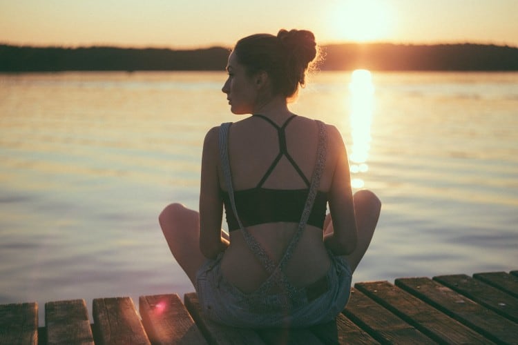 Wellness influencer sat on the dock of a lake during sunset