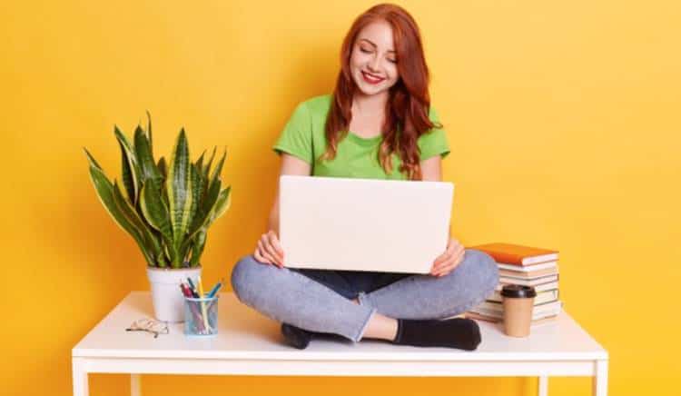 Redhead woman sitting on table with laptop